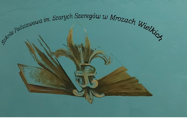 Logo szkoły- lilijka harcerska leżąca na otwartej książce.