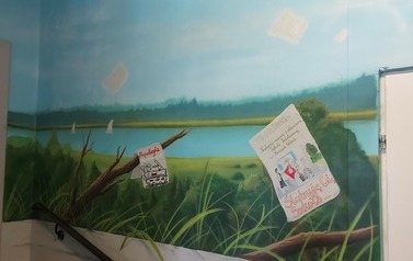 Widok na jezioro. Na gałęziach wiszą kartki, na kt&oacute;rych zapisano datę wybuchu II wojny światowej oraz datę nadania Imienia Szkole. daty