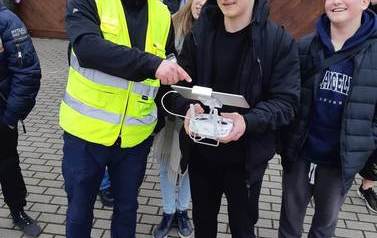 Uczeń, pod kierunkiem instruktora, steruje dronem.