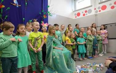 Na pierwszym planie dziewczynka ubrana na zielono - wiosna. Za nią grupa występujących dzieci.