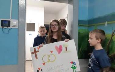 Uczennica klasy sz&oacute;stej prezentuje wykonany plakat na temat małżeństwa.