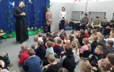 Młodzież bierze udział w spotkaniu z księdzem.