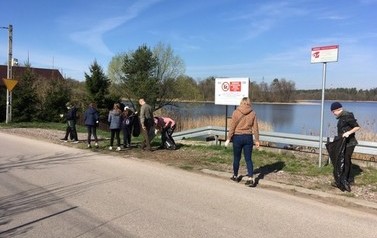 Uczniowie sprzątają teren przy jeziorze.