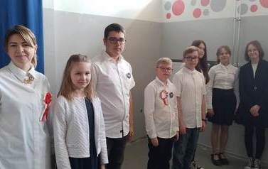 Od lewej dyrektor szkoły wraz ze zwycięzcami poszczeg&oacute;lnych klas: uczennica z klasy IV, uczeń z klasy VIII, uczeń z klasy V, uczeń z klasy VI, dwie uczennice z klasy VII, uczennica z klasy VIII oraz nauczyciel matematyki.