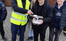 Uczeń, pod kierunkiem instruktora, steruje dronem.