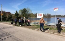 Uczniowie sprzątają teren przy jeziorze.