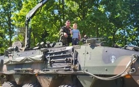 Uczeń pozuje na pojeździe wojskowym.